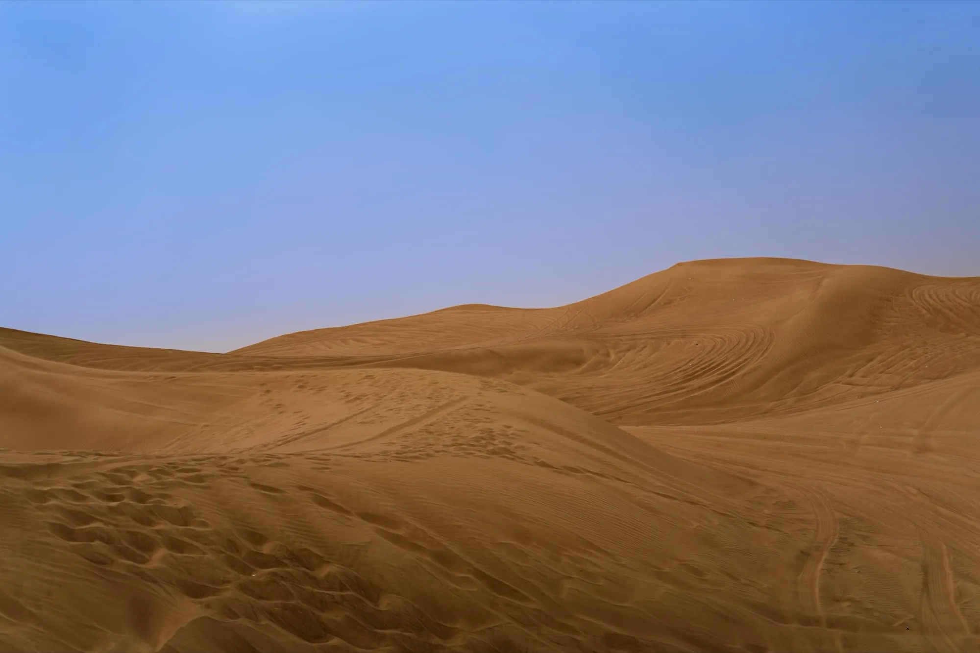 Sand dunes in the Dubai desert with an off-road vehicle on the ridge