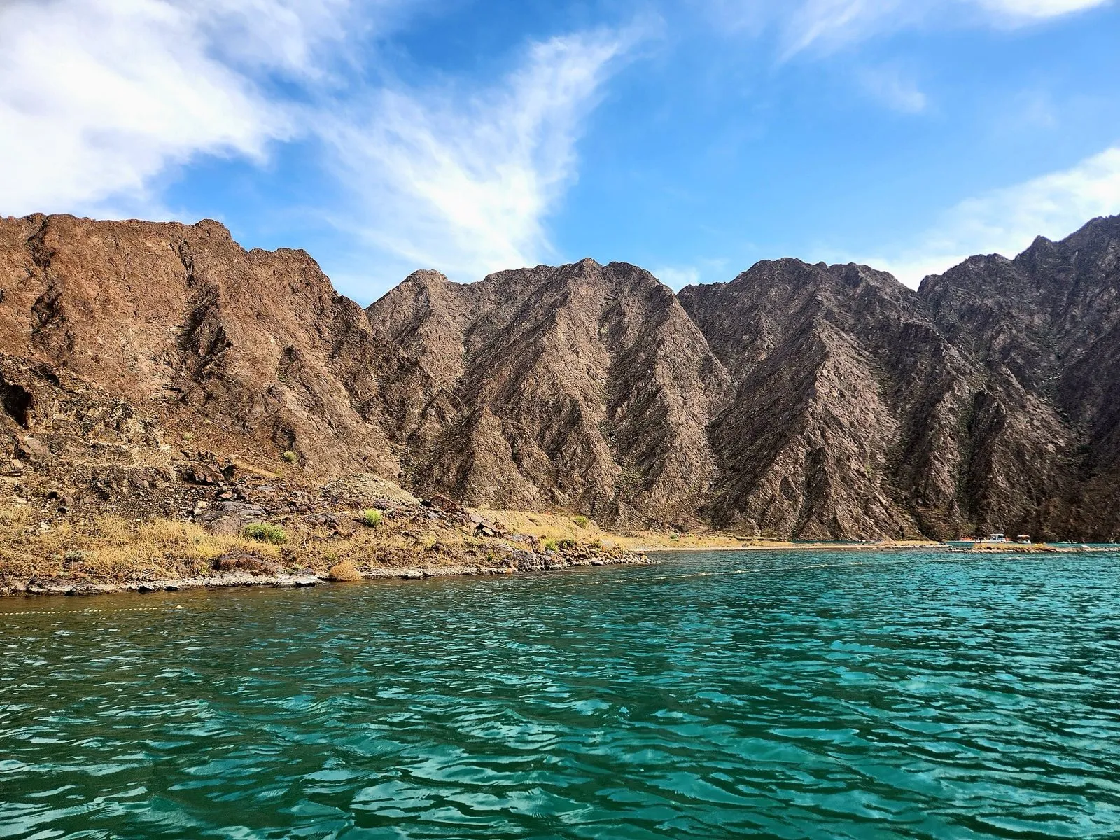 Brown Hajar mountains rising above the turquoise water of Hatta Dam, Dubai Emirate