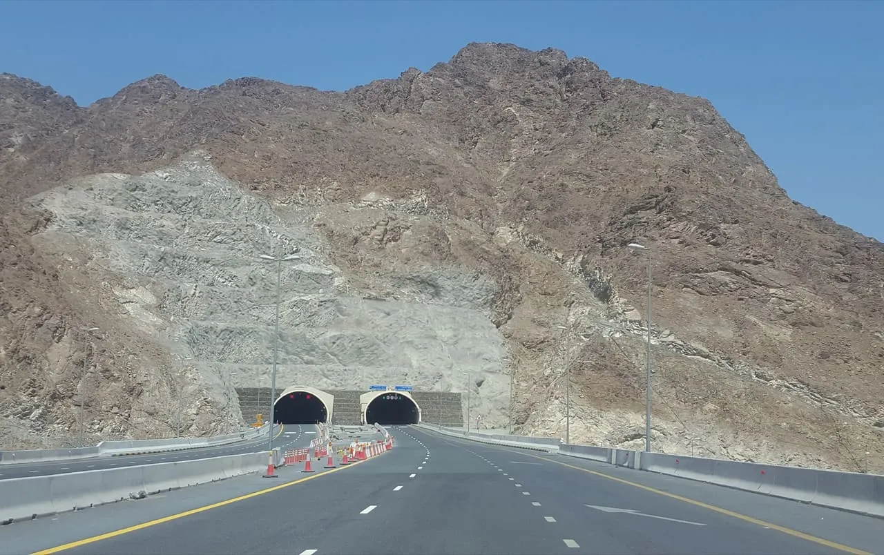 Twin road tunnels cut through a rocky mountain on the highway to Fujairah