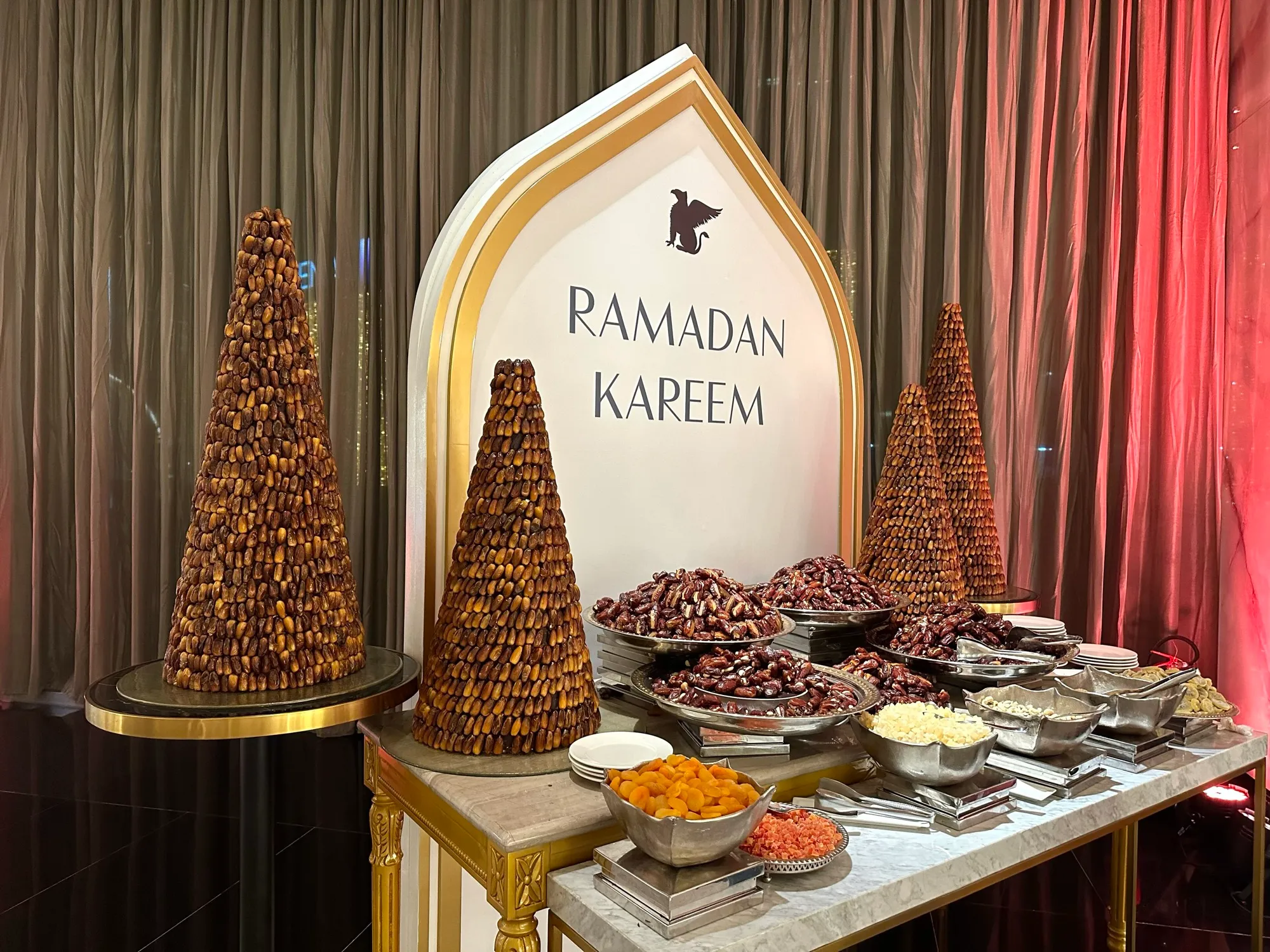 Towers of dates and bowls of dried fruit at a Ramadan Kareem iftar buffet
