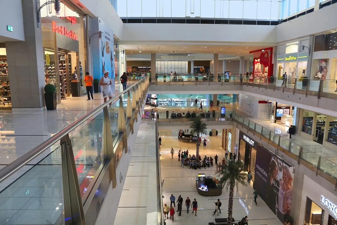 Shoppers on two levels of the Dubai Mall, with palm trees in the atrium below
