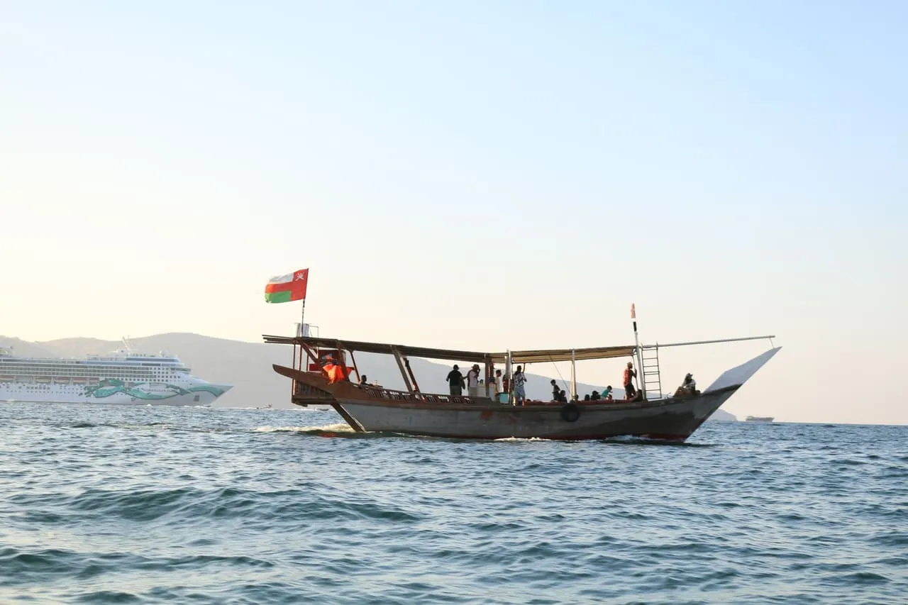 A wooden dhow flying the Omani flag on the water off Khasab in Musandam