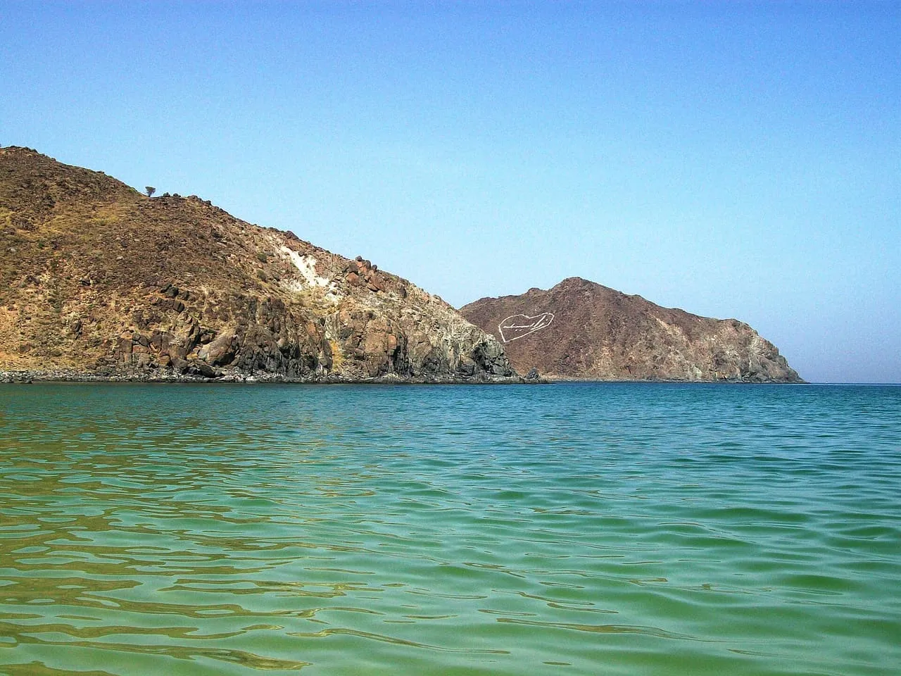 Rocky headlands dropping into clear green water of the Gulf of Oman at Khor Fakkan