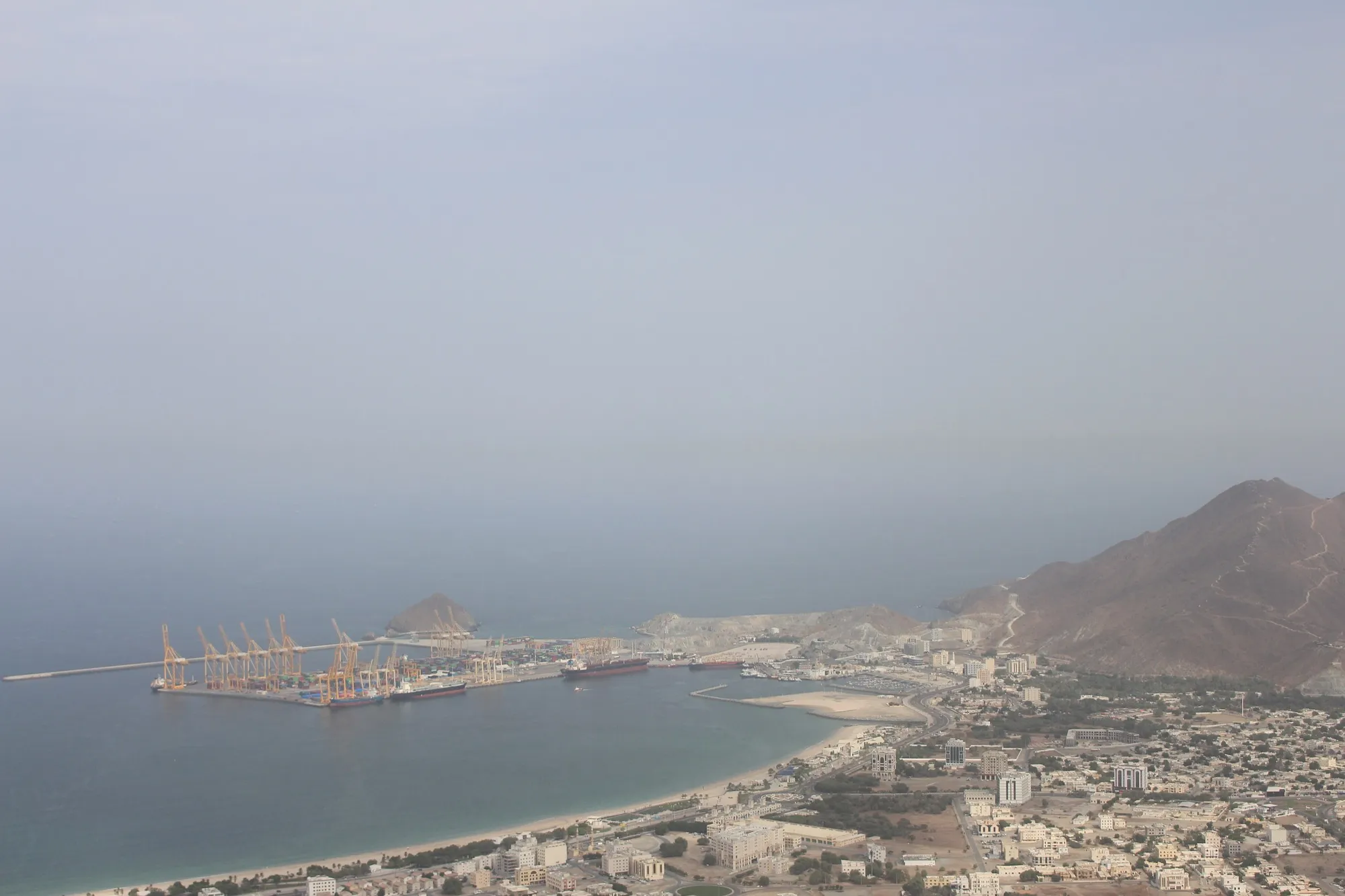 Khor Fakkan from above, with its container port, beach and the mountains behind