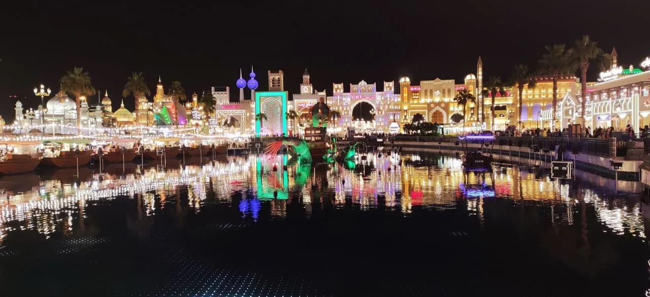 Lit-up pavilions for Kuwait, Yemen and Bahrain reflected in the Global Village lake at night