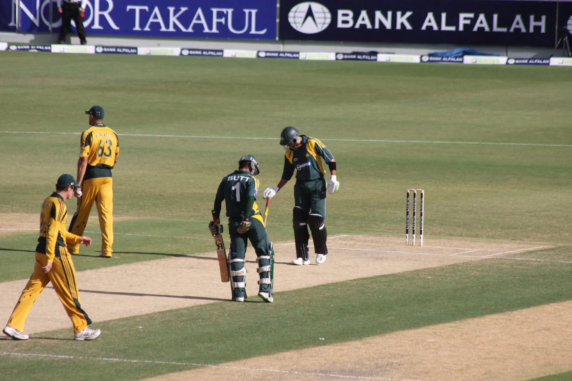 Pakistan batters and Australian fielders on the pitch at Dubai International Cricket Stadium