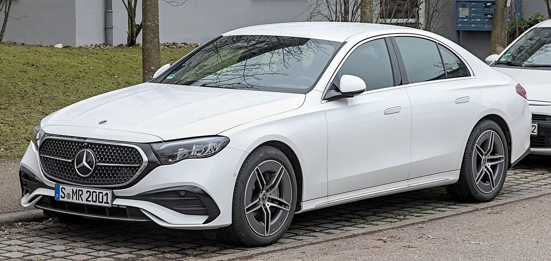A white Mercedes-Benz E-Class saloon parked on a street, seen from the front left