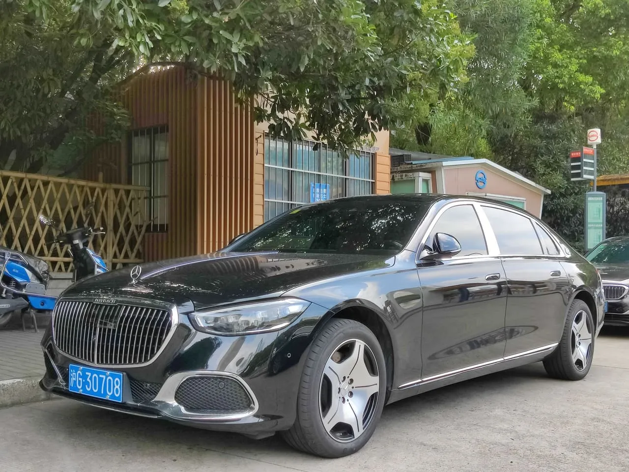 A black Mercedes-Maybach S-Class sedan parked under trees