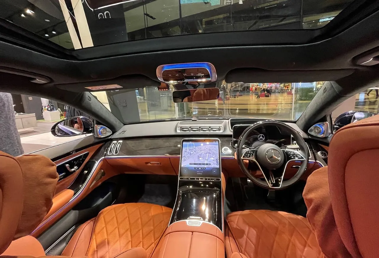 The cabin of a long-wheelbase Mercedes-Benz S 580 seen from the rear seat, with tan quilted leather and a large central touchscreen