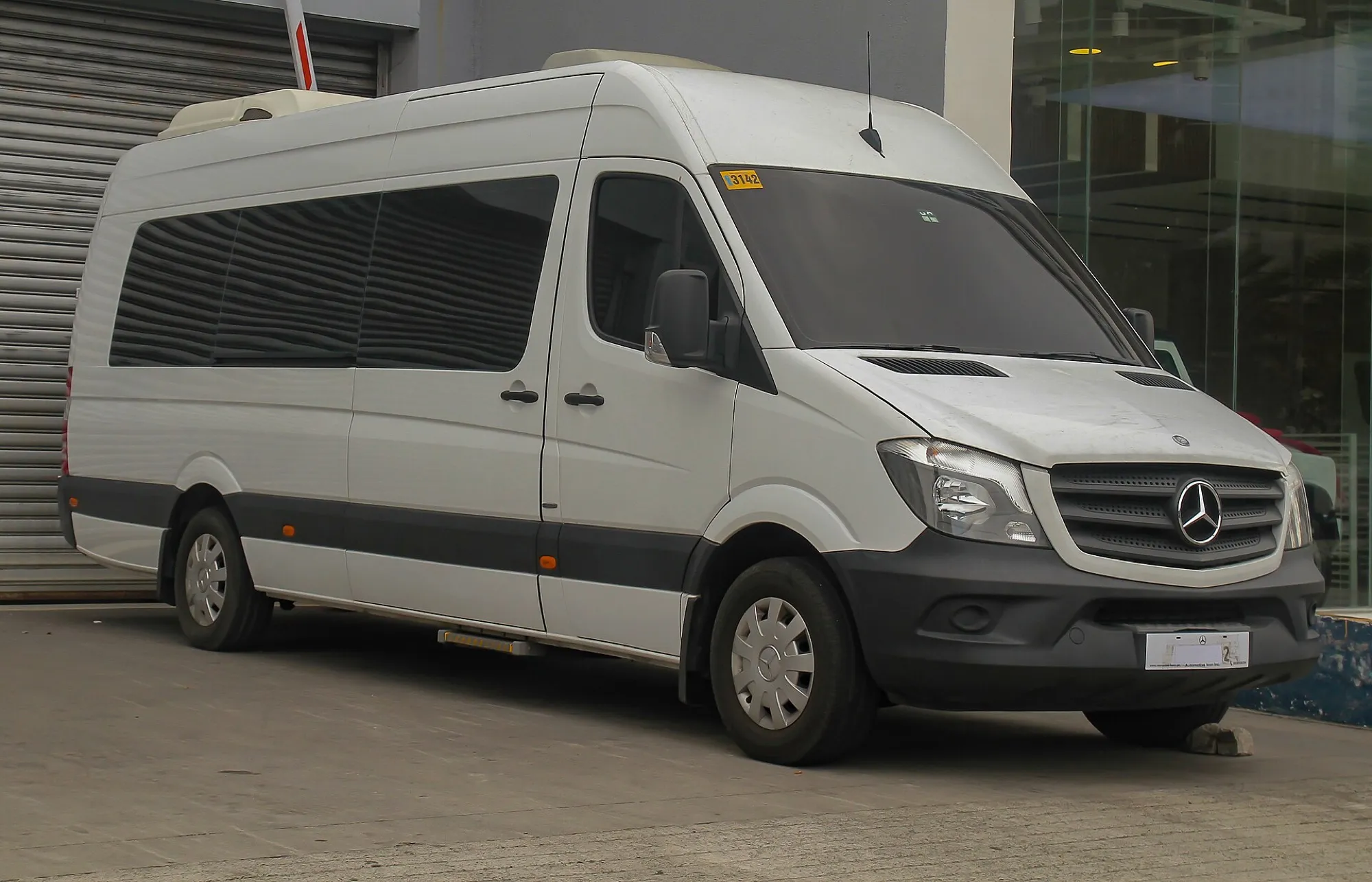 A white high-roof Mercedes-Benz Sprinter minibus with tinted passenger windows