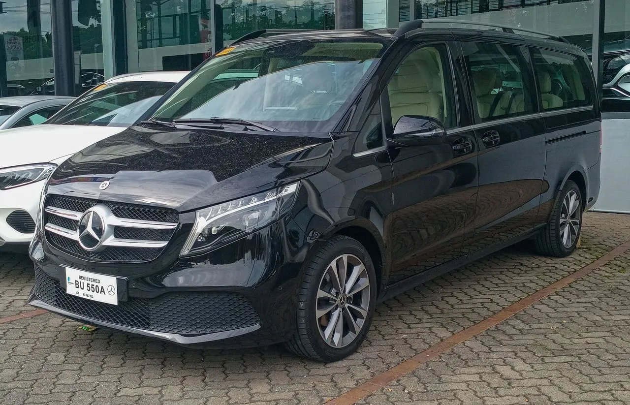 A black Mercedes-Benz V-Class people carrier with sliding side doors, parked outside a car showroom