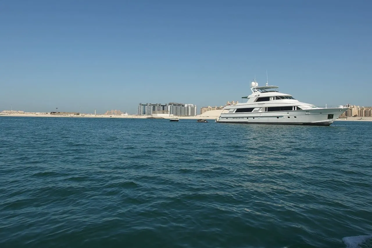 A white motor yacht at anchor off Palm Jumeirah, with Atlantis The Palm on the skyline