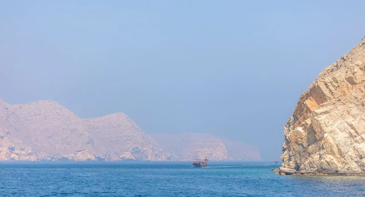 A dhow sailing between the cliffs of a fjord on the Musandam Peninsula, Oman