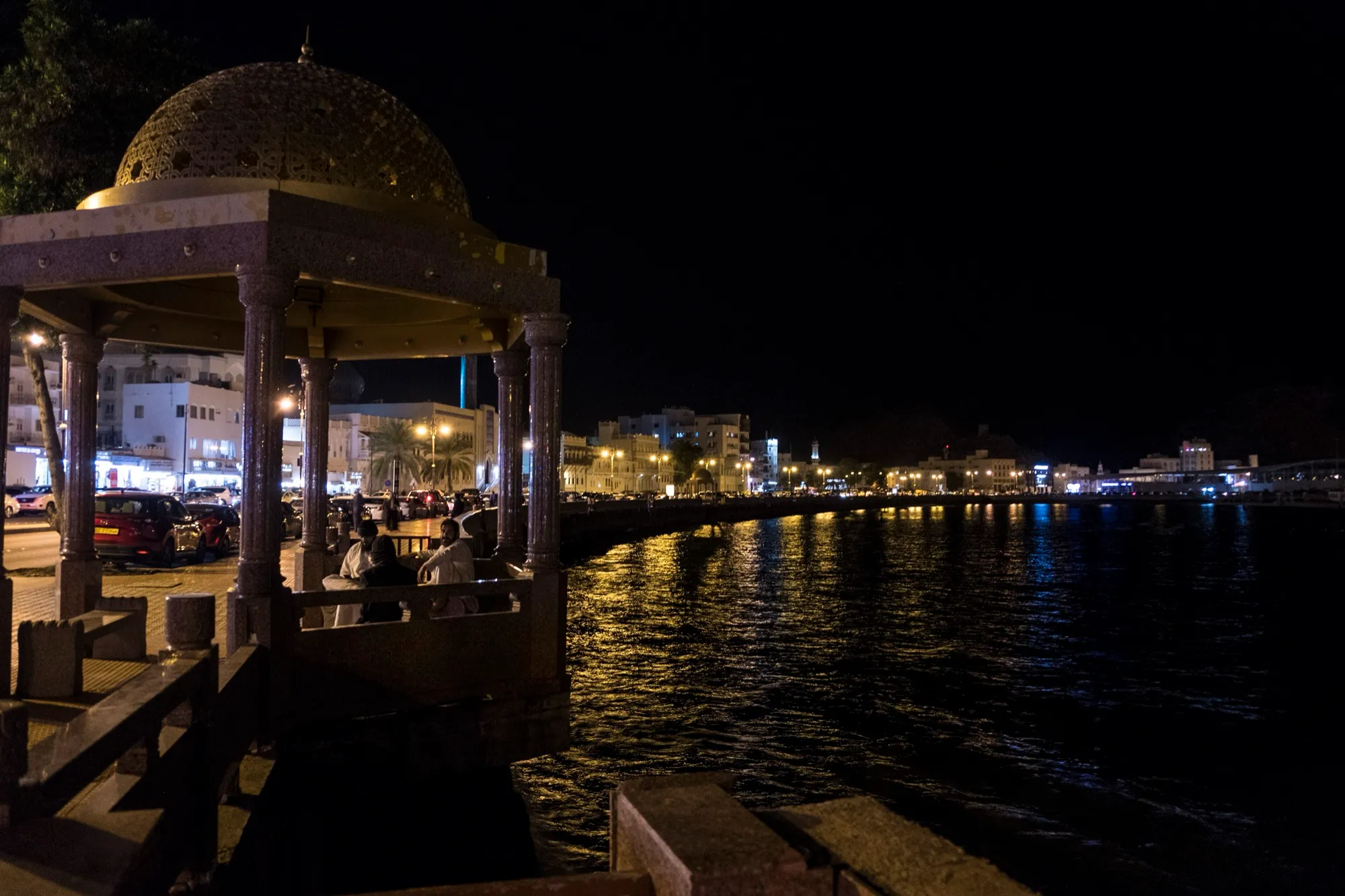 Muttrah Corniche waterfront in Muscat at night, with a domed pavilion over the sea wall