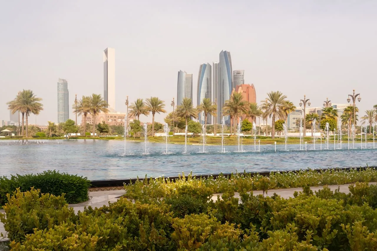 The Etihad Towers and downtown Abu Dhabi seen across a fountain pool in the gardens of Qasr Al Watan