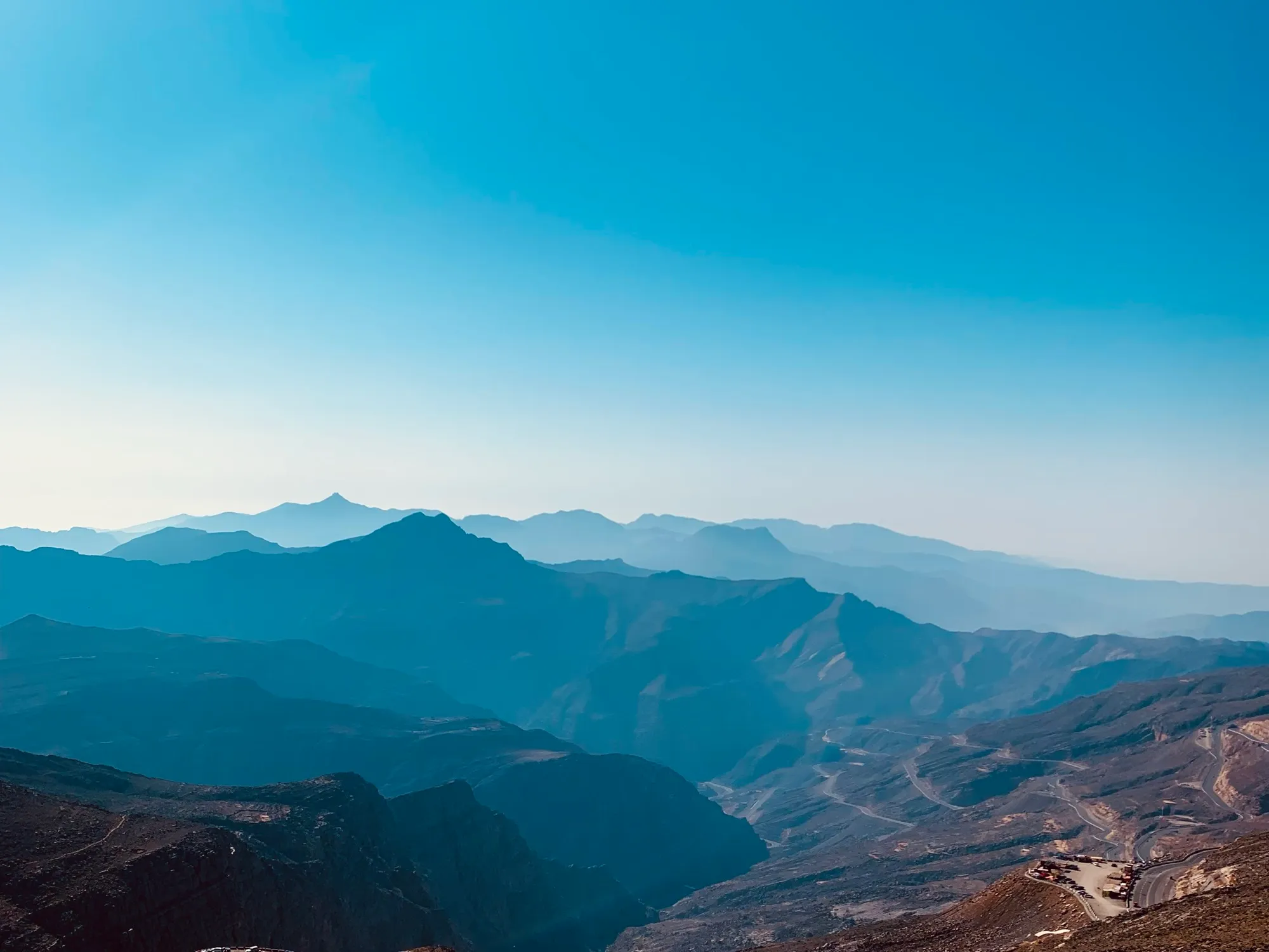 Layered blue ridgelines of the Hajar Mountains seen from a Jebel Jais viewpoint