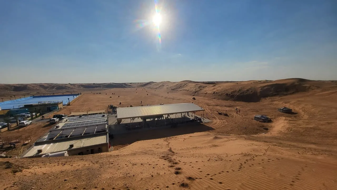 A riding base with shaded seating beside open red dunes in the Dubai desert