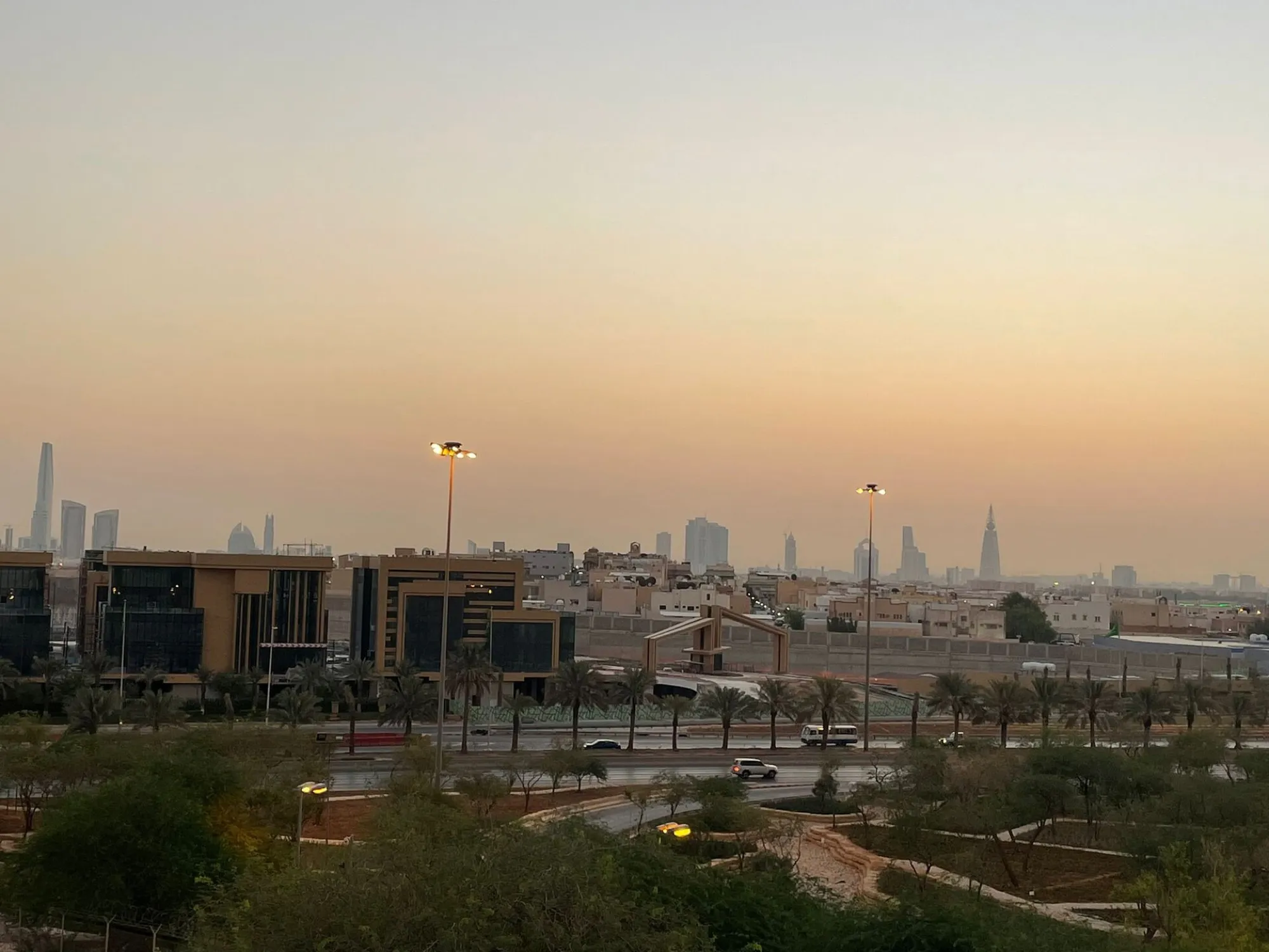 The Riyadh skyline at dusk, seen over a landscaped highway