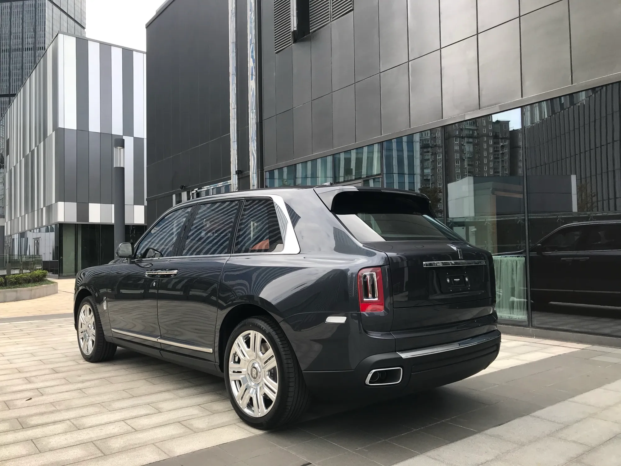 Rear three-quarter view of a dark grey Rolls-Royce Cullinan showing its rear doors and tailgate