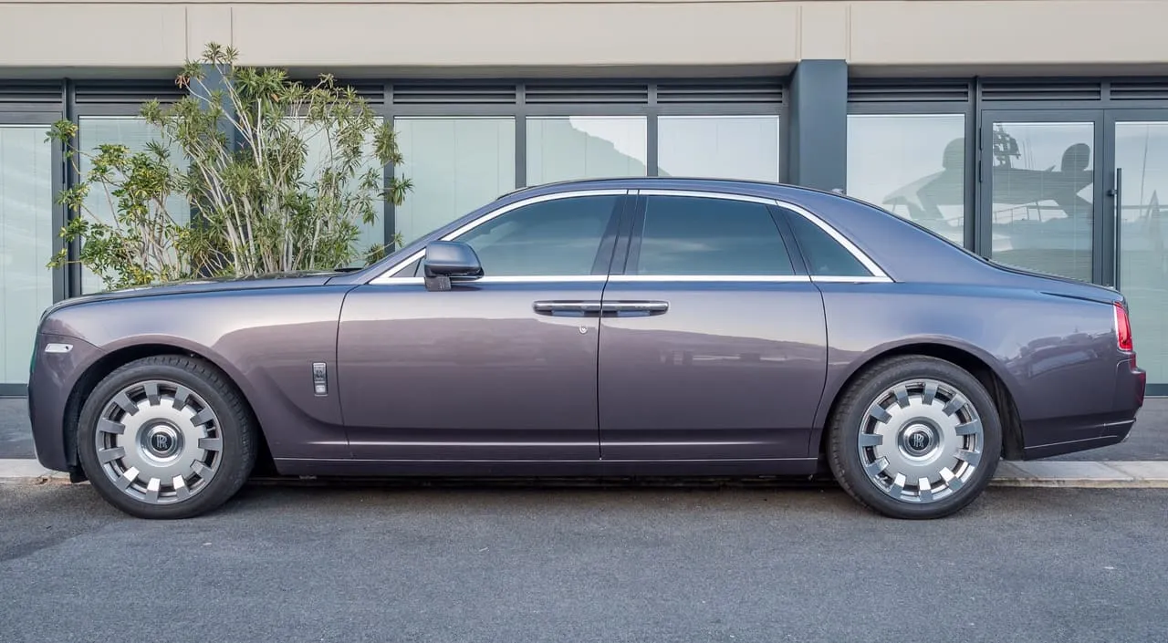 A Rolls-Royce Ghost sedan in side view, parked on a street