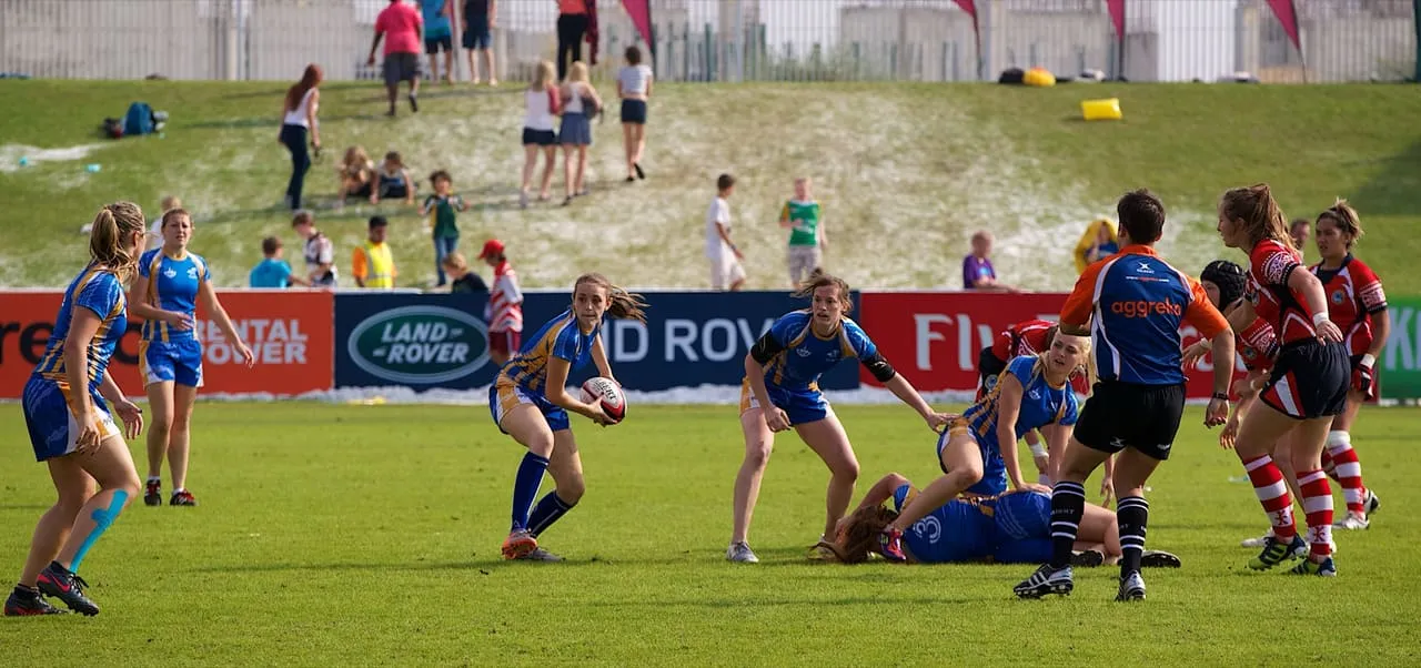 A women’s rugby sevens match at the 2012 Dubai Rugby Sevens, with fans on the grass bank behind