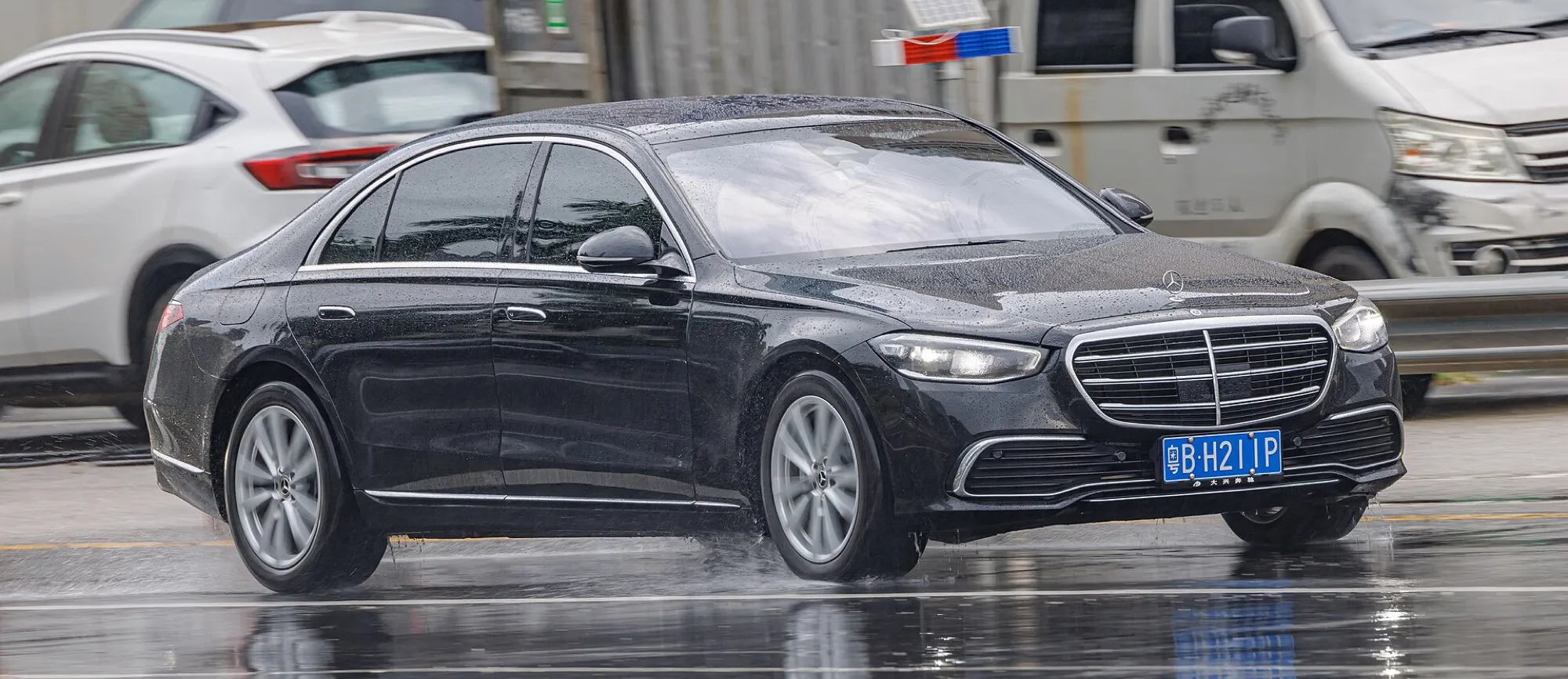 A black Mercedes-Benz S-Class (W223) saloon driving in the rain