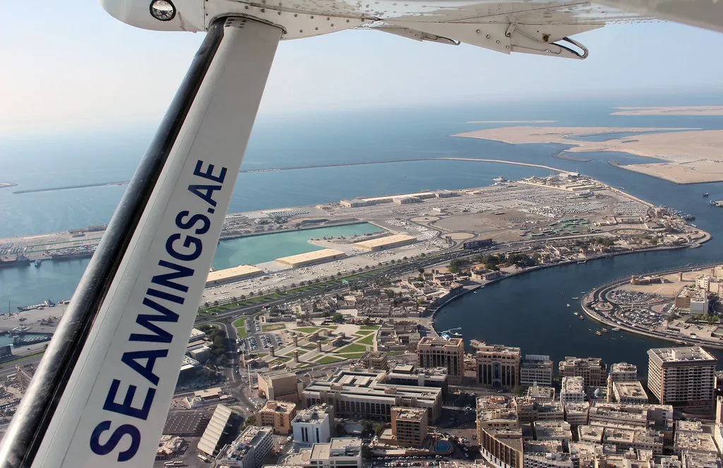 View from a Seawings seaplane over Deira and the mouth of Dubai Creek, with the wing strut in the foreground