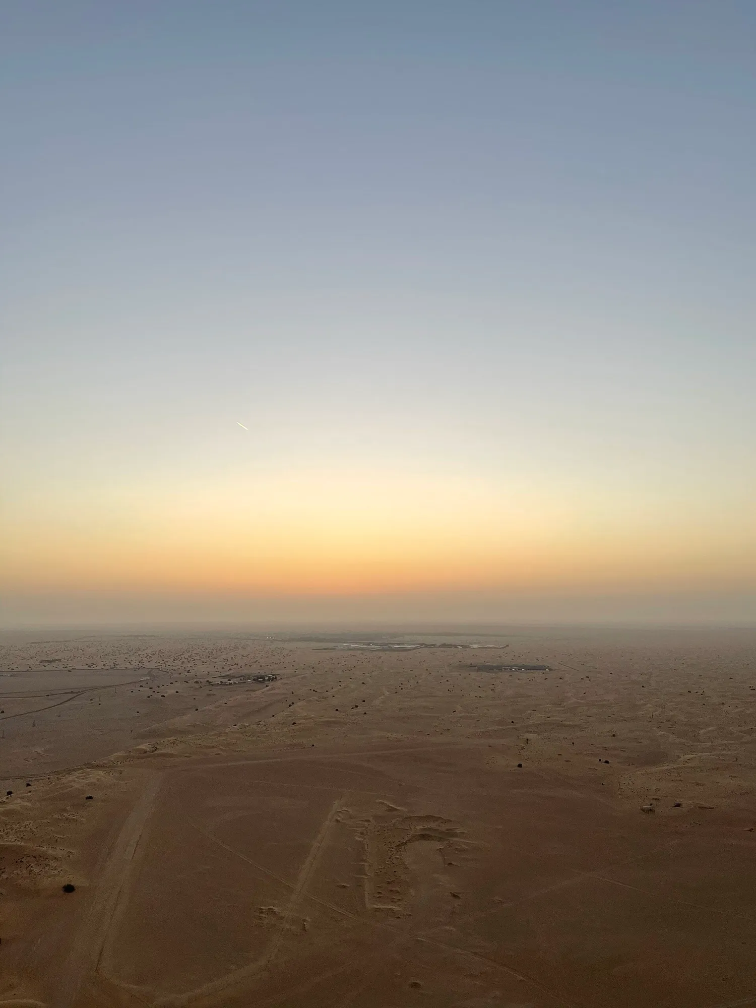Sunrise over flat desert, seen from a hot air balloon basket above Dubai