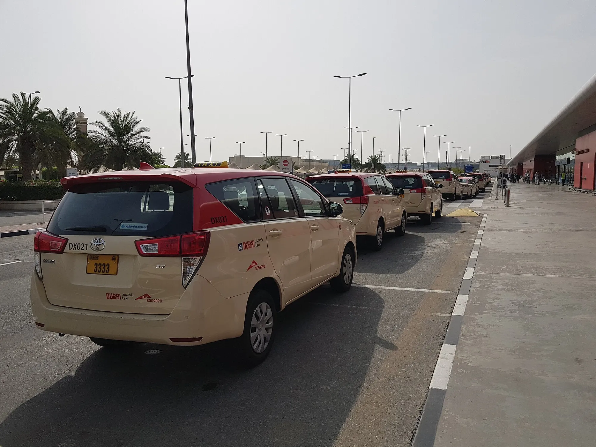 Licensed taxis and black chauffeur cars waiting under the canopy outside Dubai Airport Terminal 2