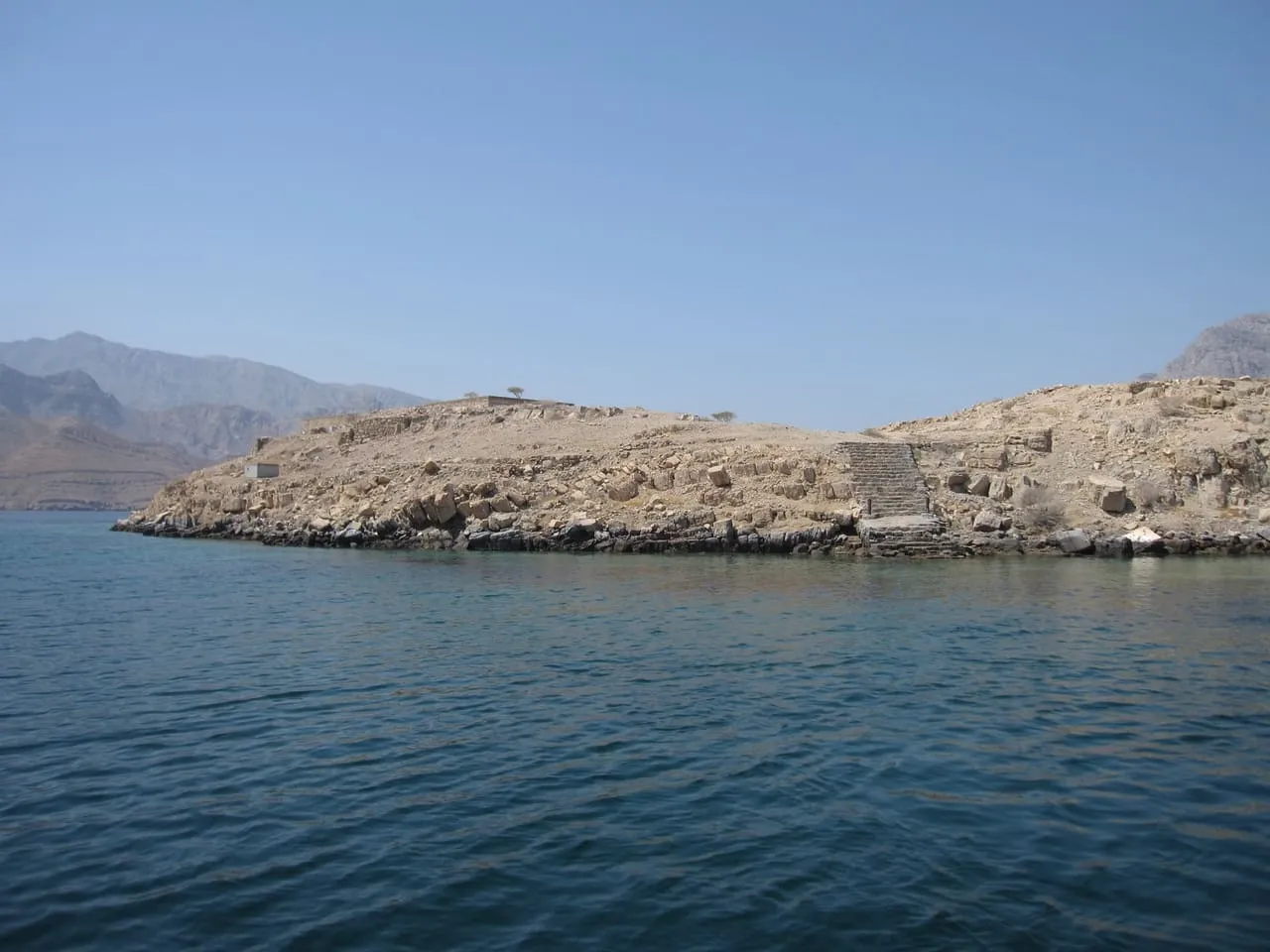 Telegraph Island in Khor Ash Sham, with the stone steps and ruins of the old telegraph station, seen from a dhow