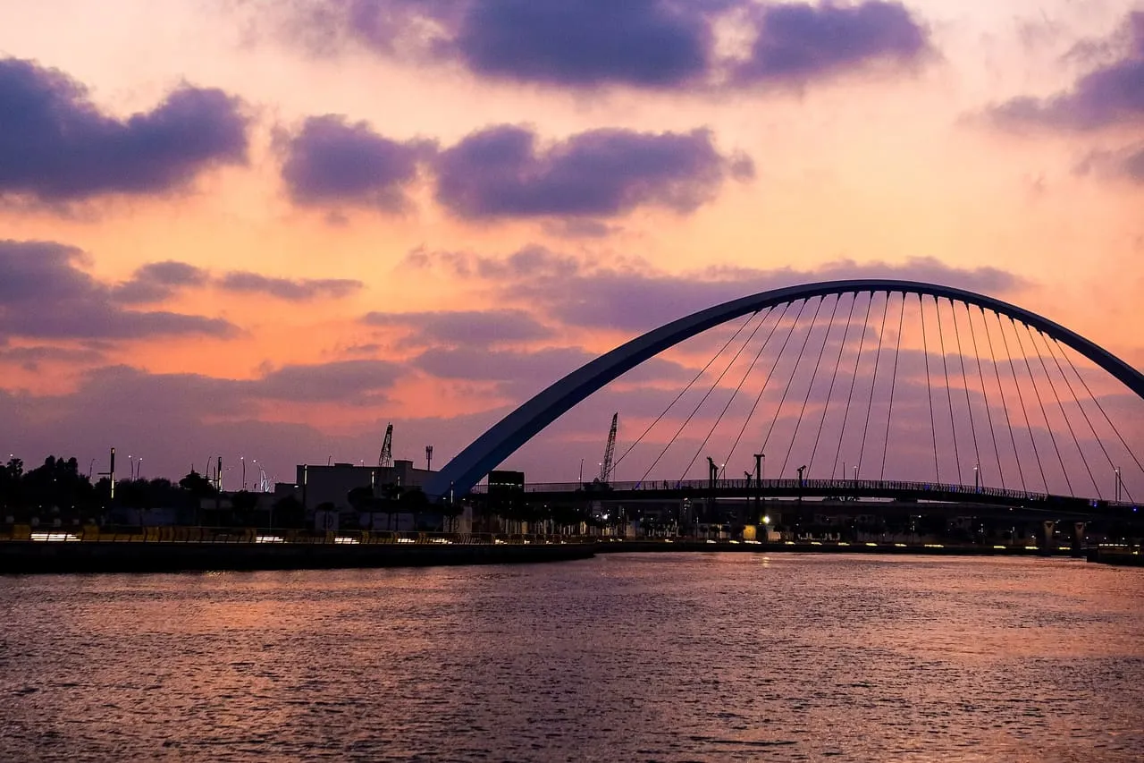 The arched Tolerance Bridge over the Dubai Water Canal in Business Bay, silhouetted at dusk