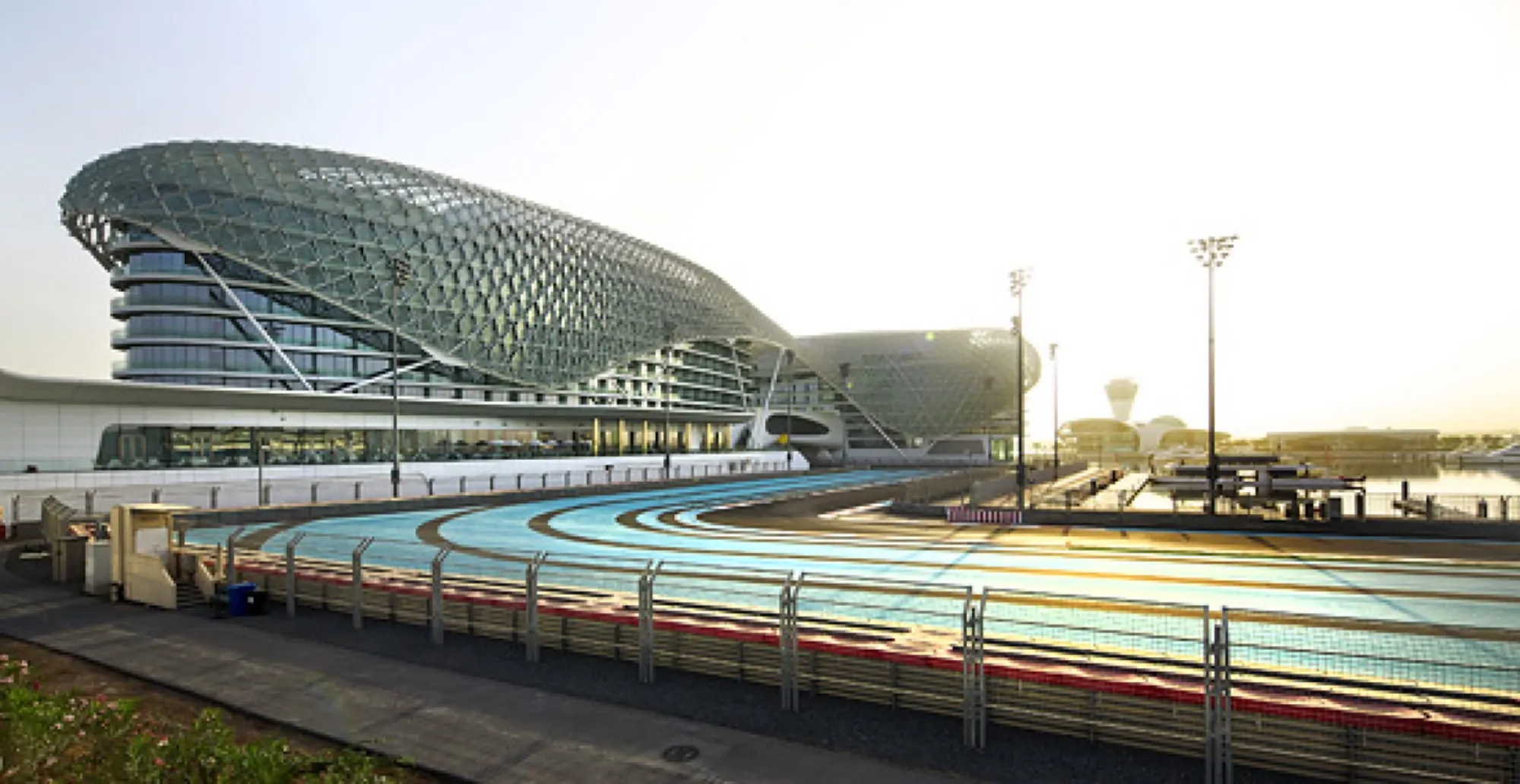 The Yas Hotel and its glass shell beside the blue-edged Yas Marina Circuit track on Yas Island