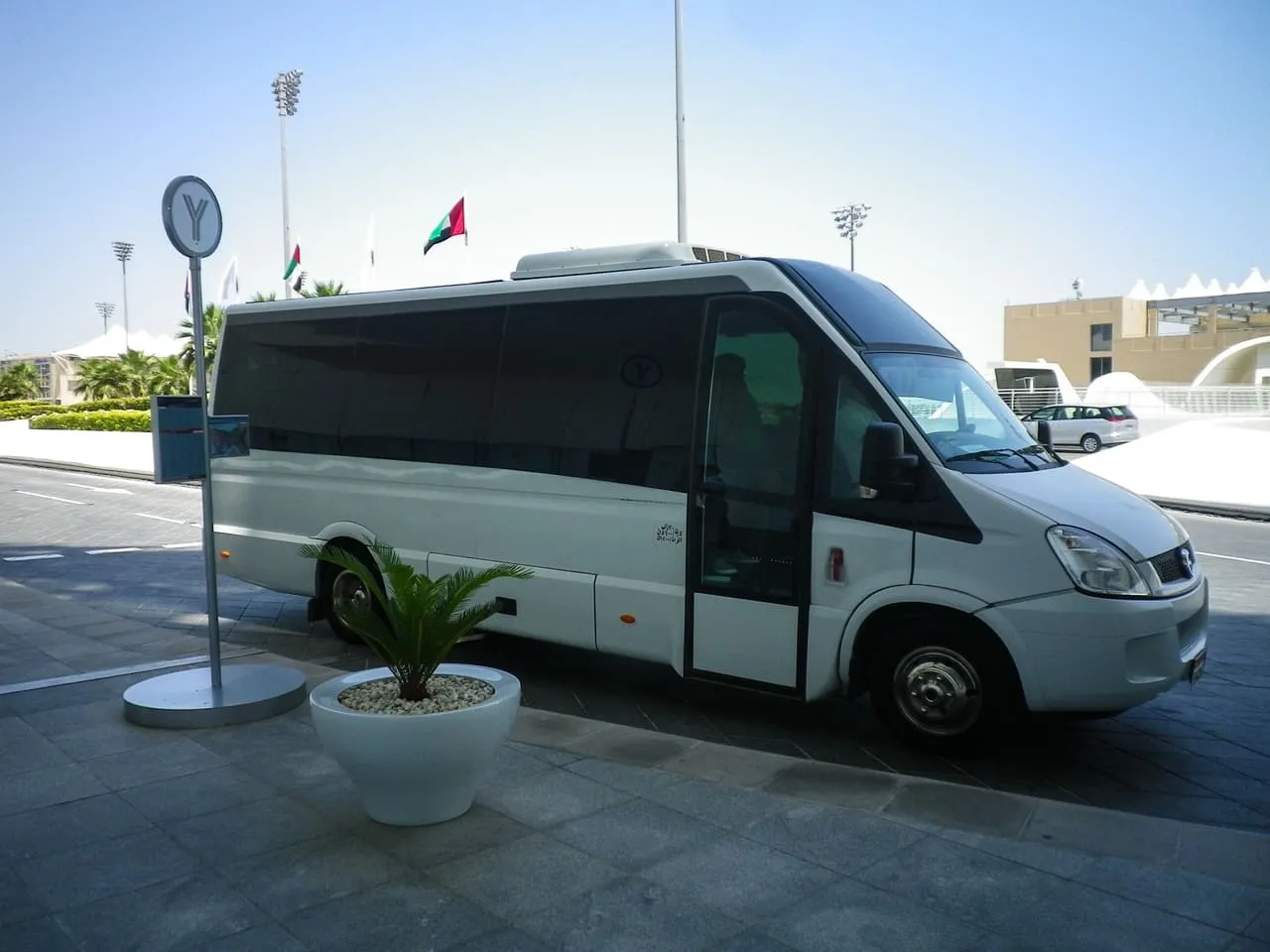 A white Yas Island shuttle minibus parked at a stop marked with a Y sign