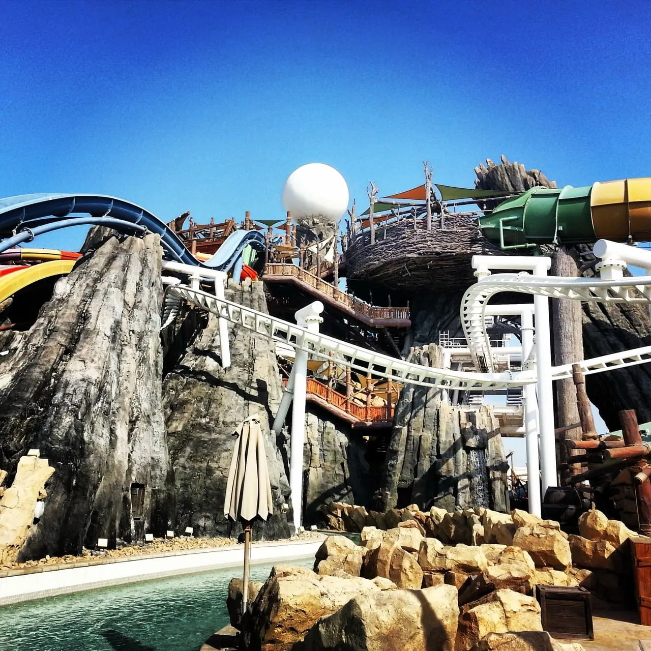 Water slides and a rock tower under a clear sky at Yas Waterworld