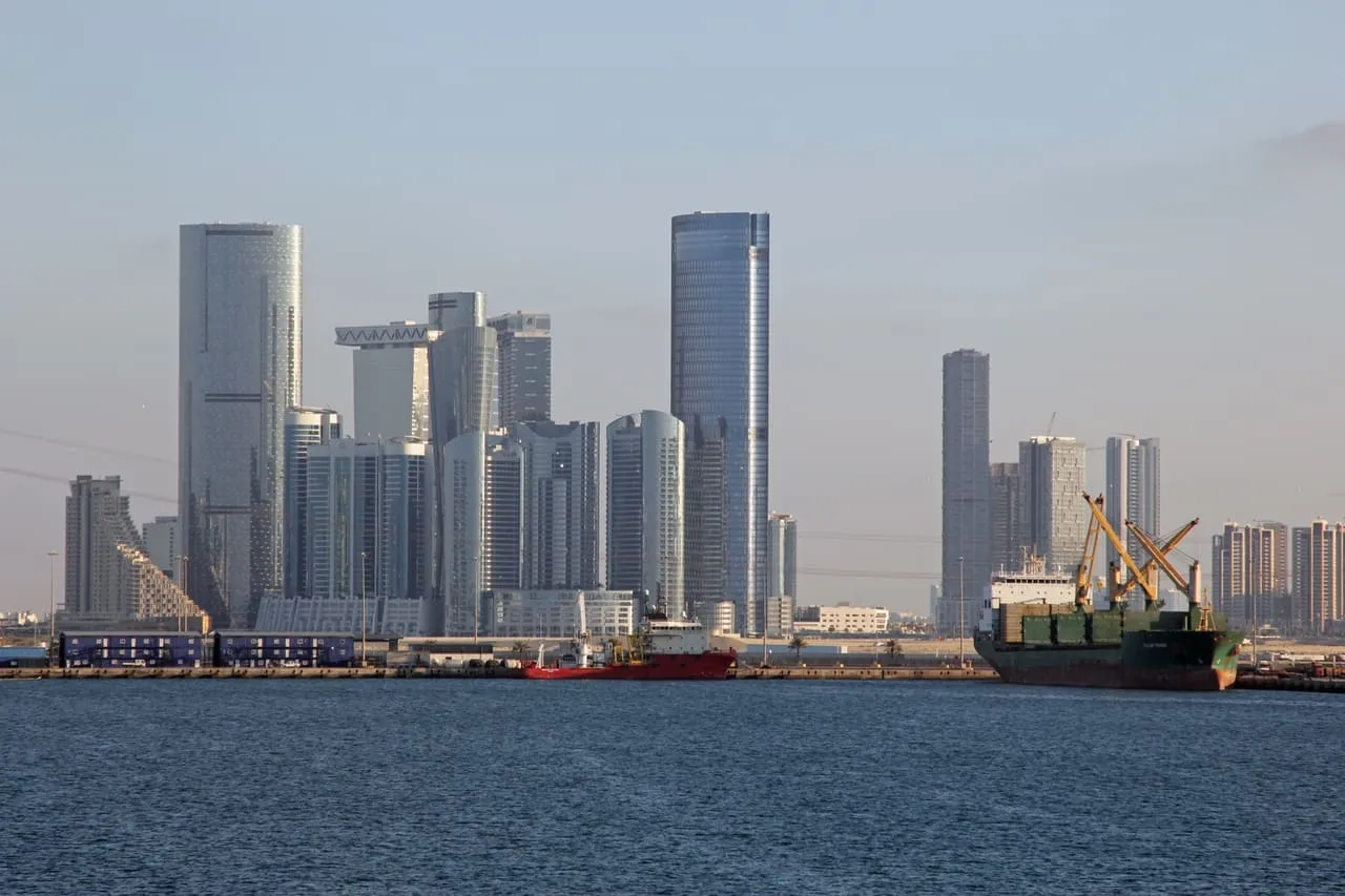 The Al Reem Island towers across the water from Zayed Port in Abu Dhabi, with a cargo ship at the quay